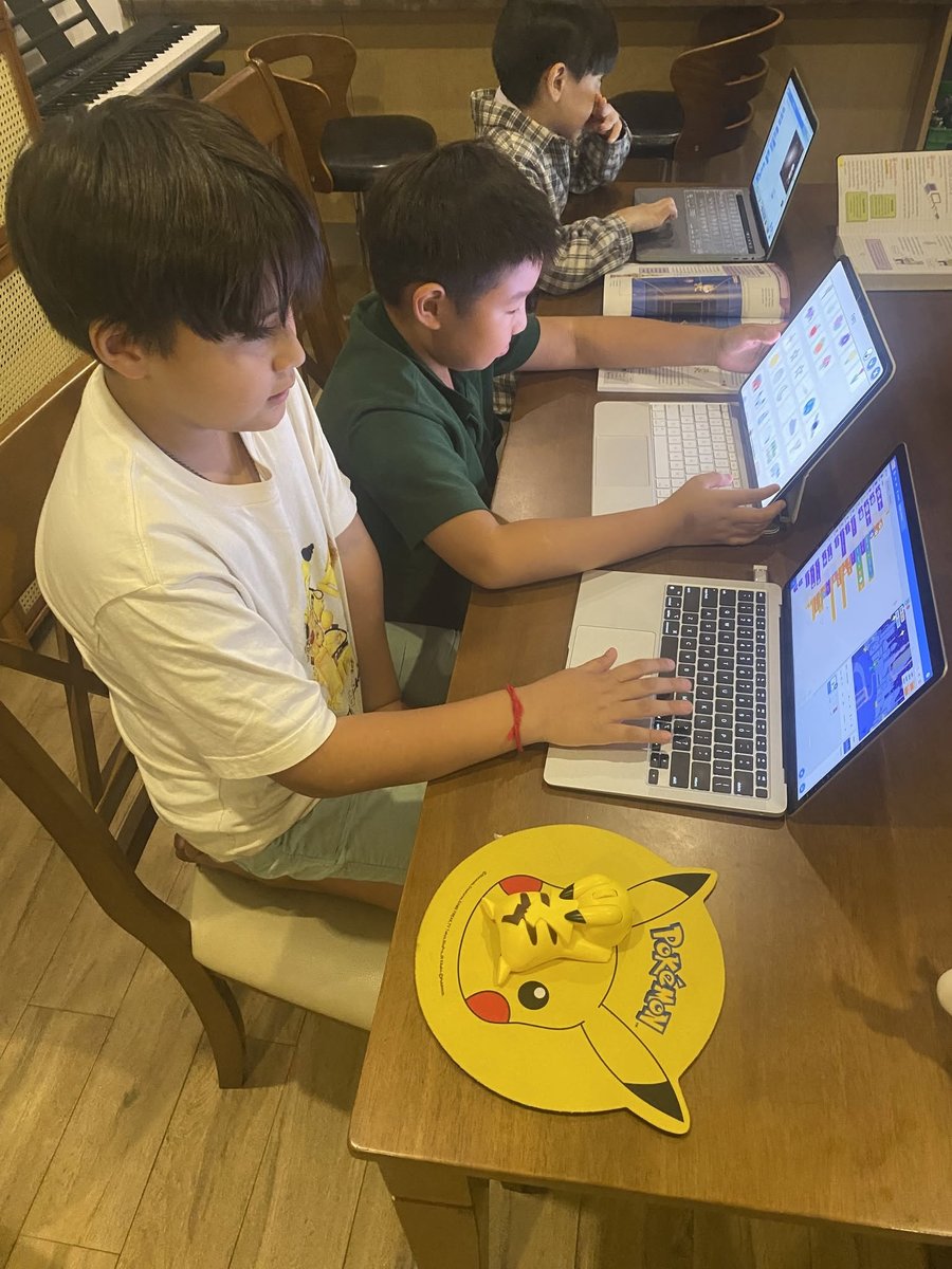 Students coding side-by-side with Scratch and Pikachu mouse in small group tutoring session